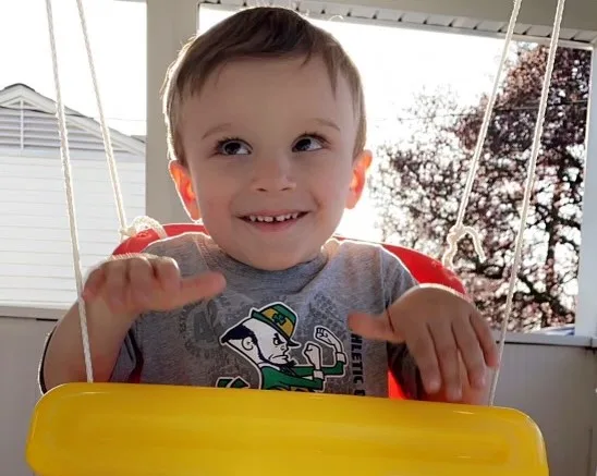 A boy in a swing smiling.