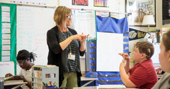A teacher and boy using sign language to communicate in a class.