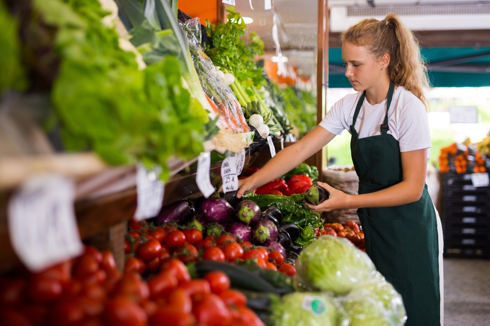 teen wearing an apron works in the produce department