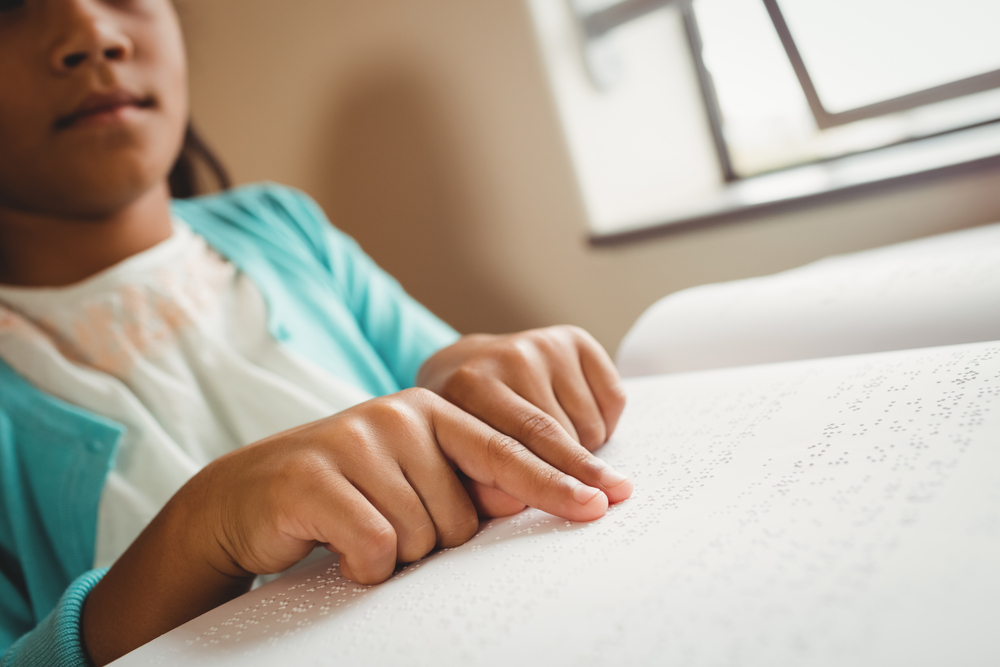 Child reads braille with pointer fingers