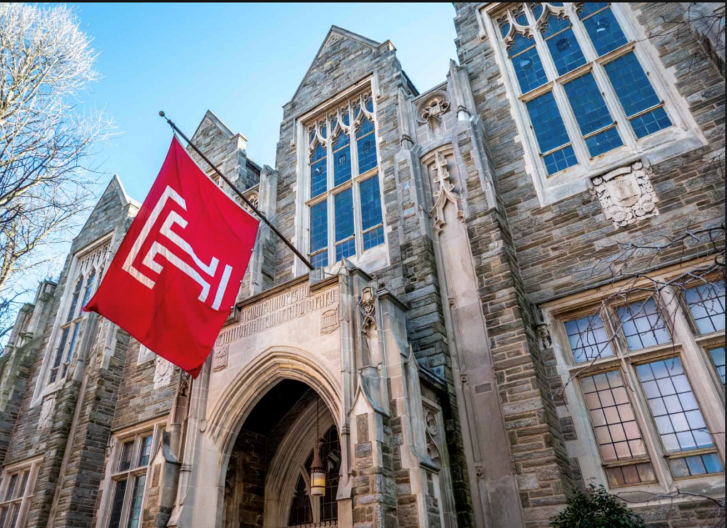 ornate stone university building with a red Temple University flag