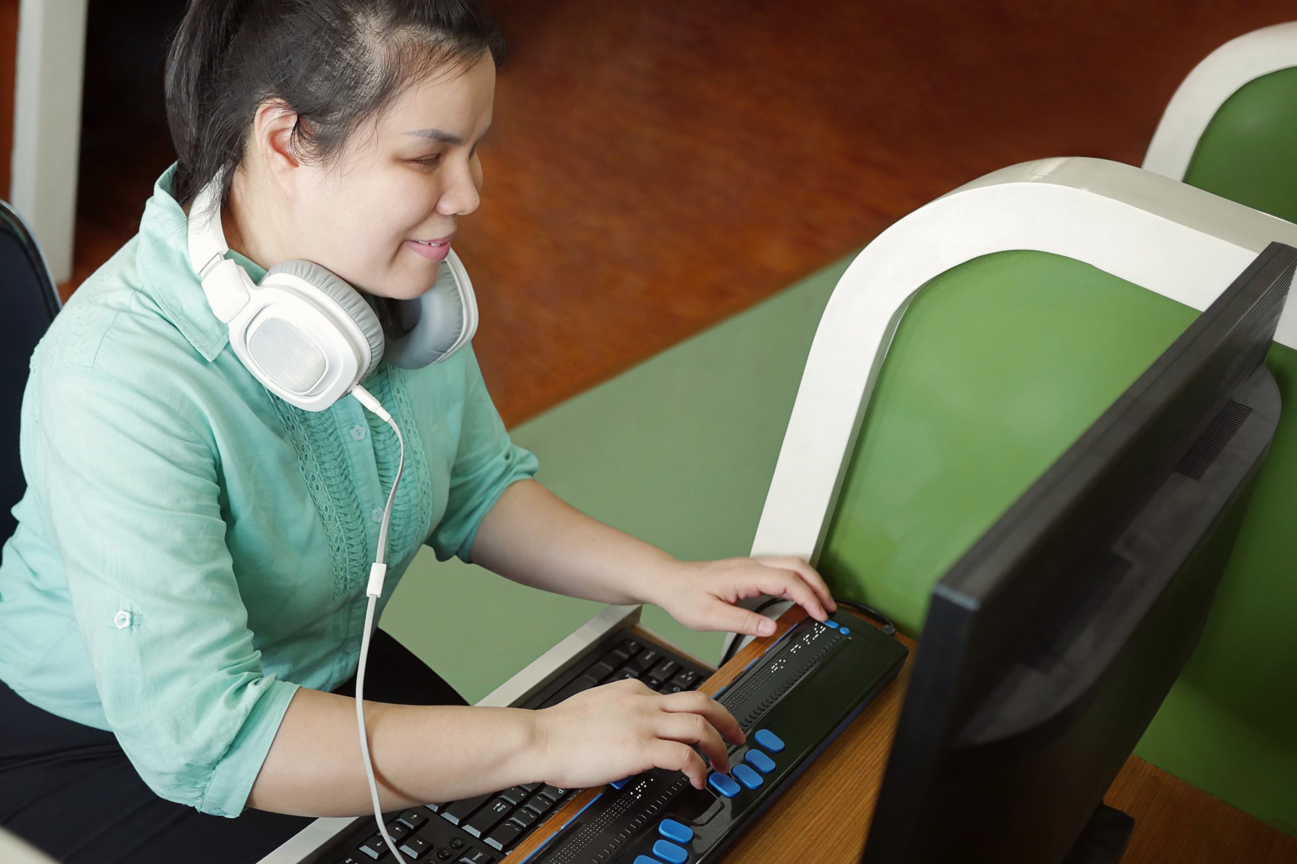 Adolescente con audífonos sentada frente a la computadora