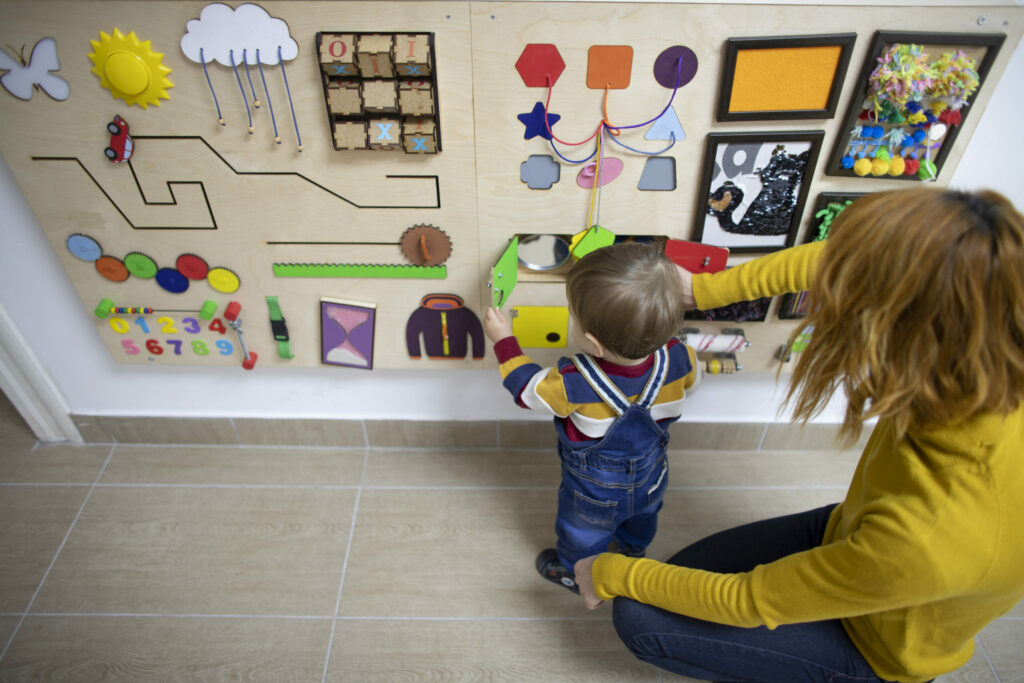 A boy exploring a sensory wall with a paremt