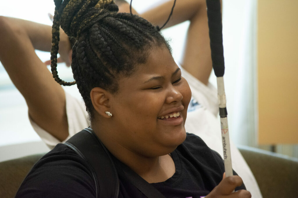 A teen smiling holding her cane.