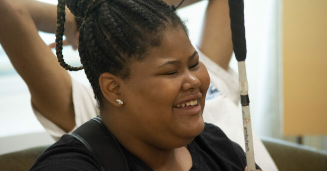A teen smiling holding her cane.