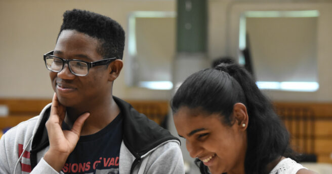 Two teens smiling during a conversation.