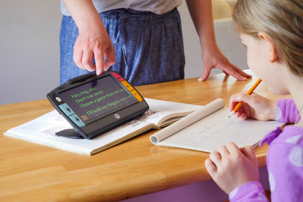 A student writing what is displayed on an enlarged screen.