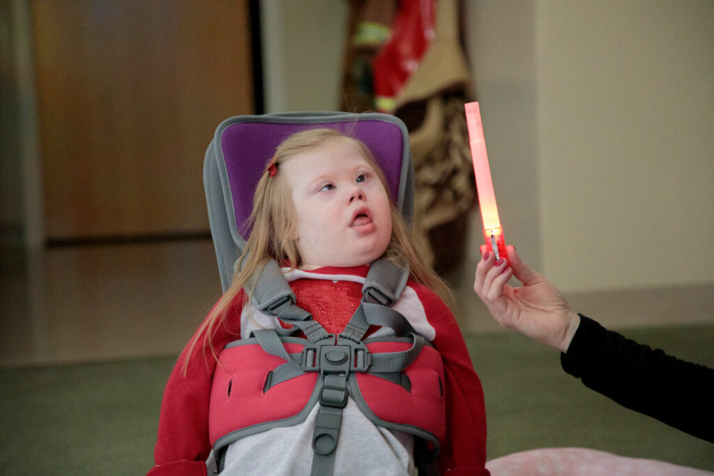 A child in supported seat looking towards alight up toy.