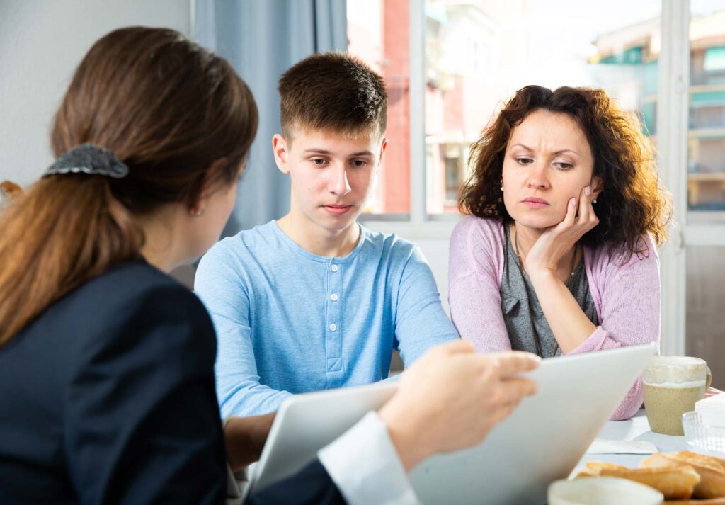 A mother and son talking to a teacher at an IEP meeting. 