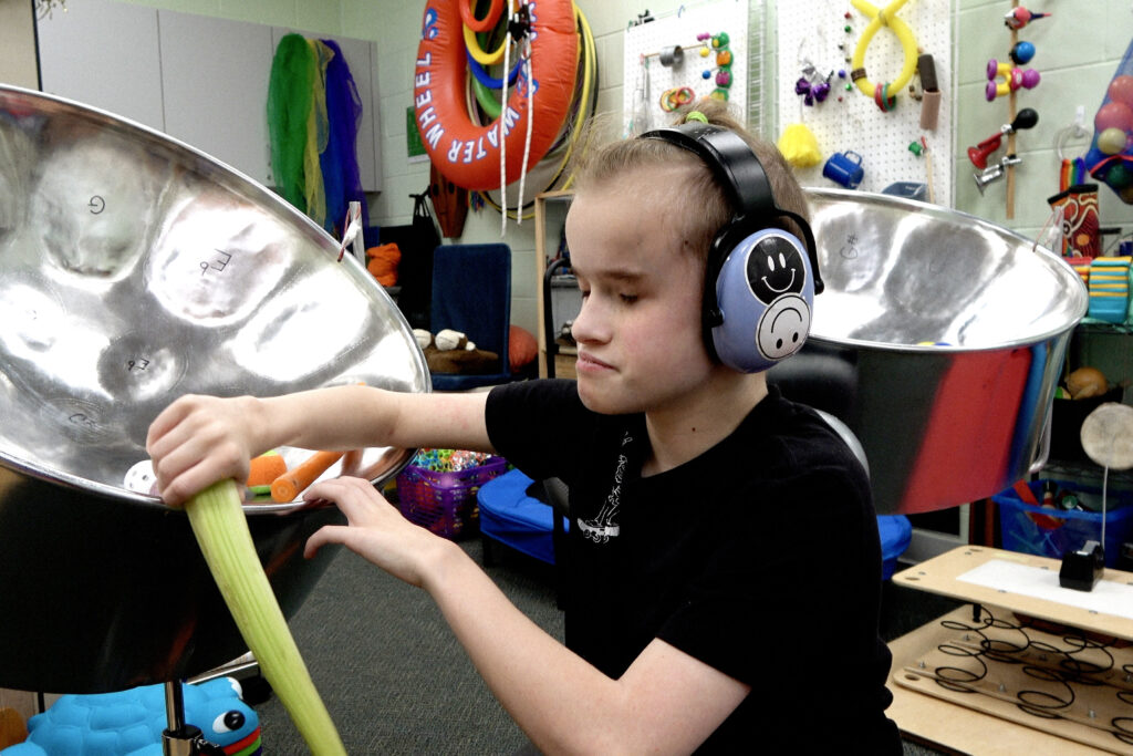 A child playing with a steel drum and various objects.