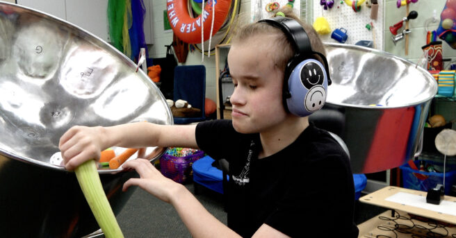 A child playing with a steel drum and various objects.