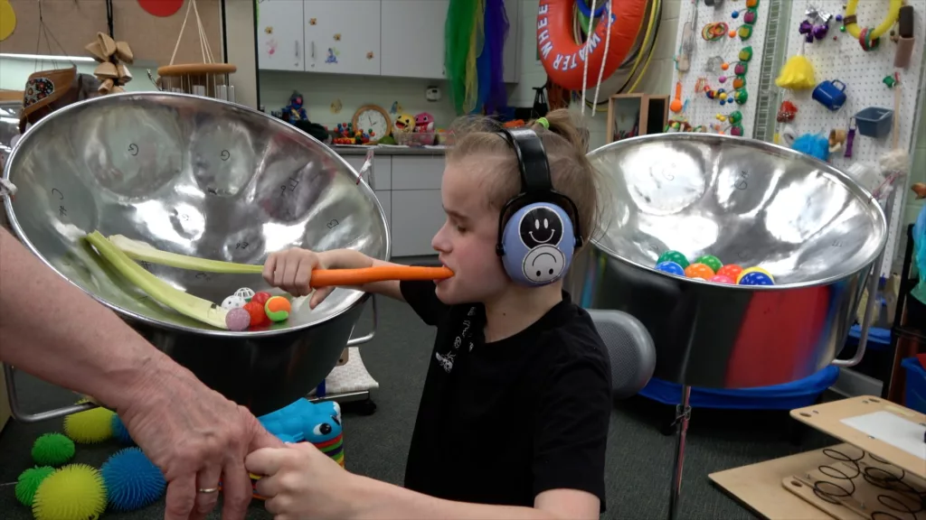 Child wearing headphones explores a carrot 