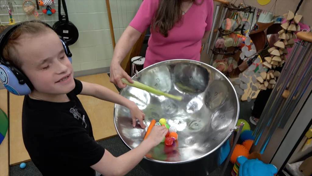 Child wearing headphones plays drums