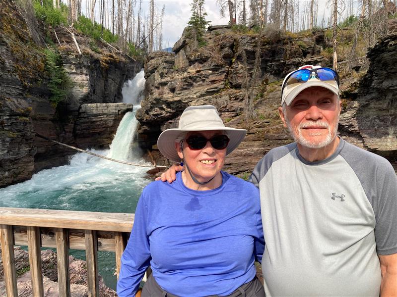 couple embracing on a bridge in front of a waterfall