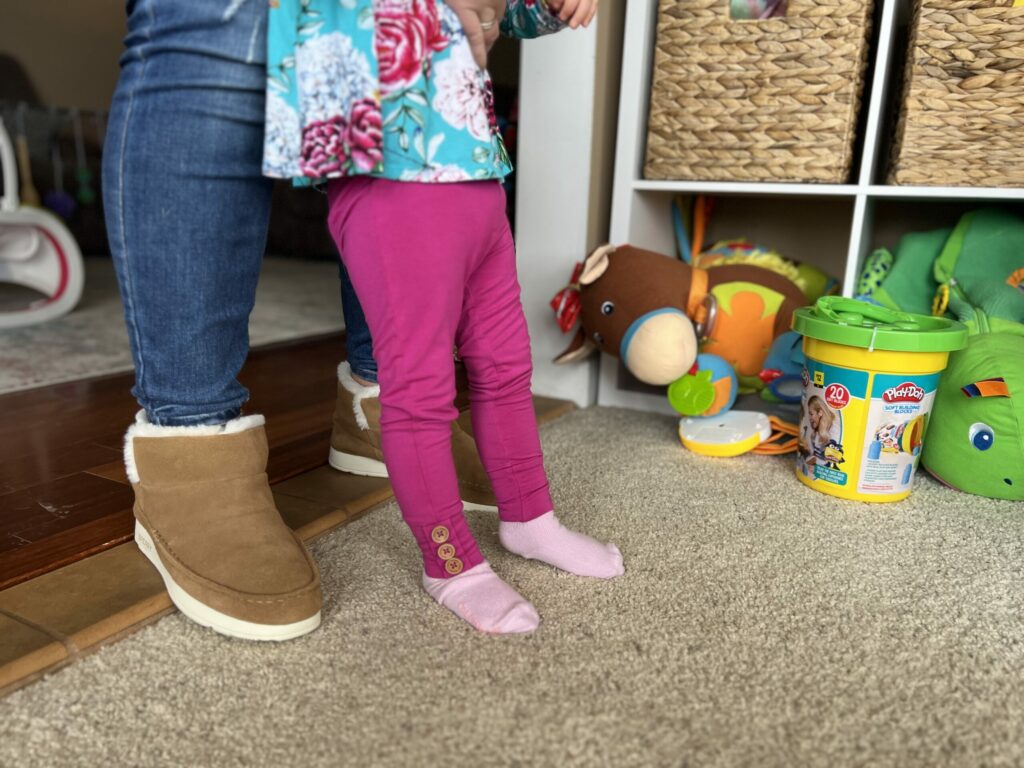 A toddler standing with support of parent.
