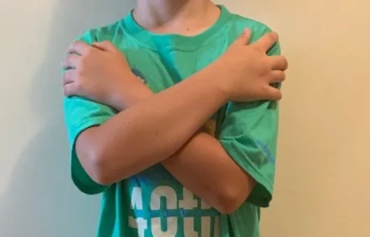 Young boy crossing his arms in front of his upper body