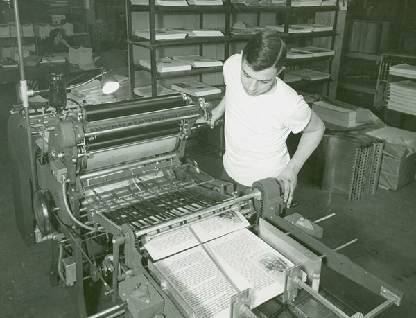 Picture from the 1960s of young man using a large printing press
