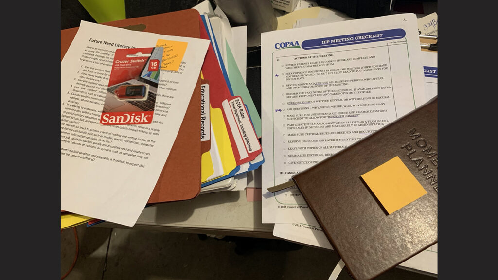 stacks of folders and documents, including a visible IEP checklist and planner