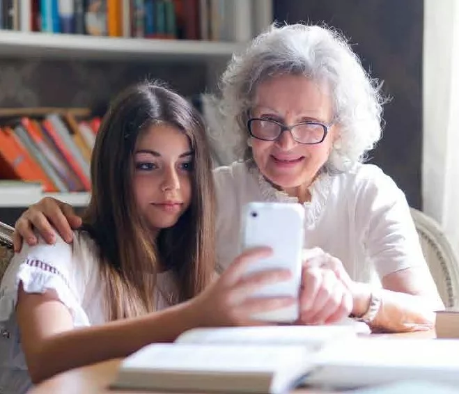 grandmother sitting with her grand daughter looking at her phone