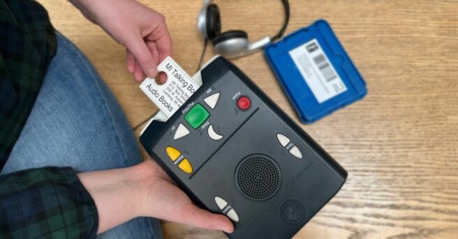 A person putting the talking library card into the reader.