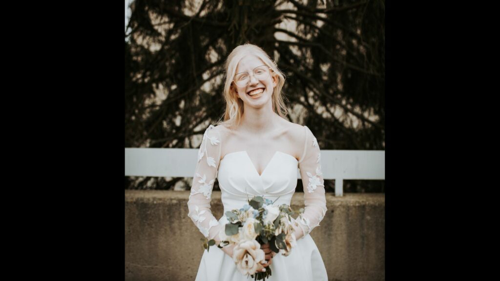 bride with fair skin and hair smiles and holds a bouquet