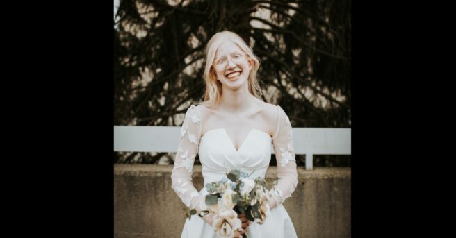 bride with fair skin and hair smiles and holds a bouquet