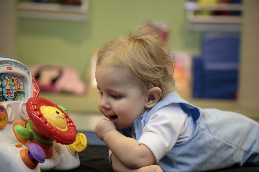 Little boy playing on his tommy with a toy.