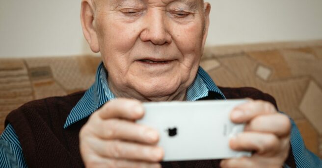 Senior adult holding a cell phone smiling