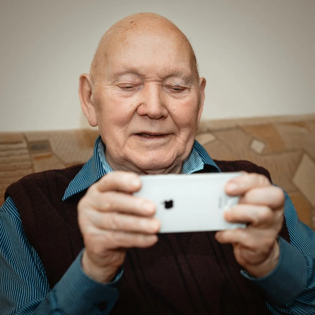 Senior adult holding a cell phone smiling