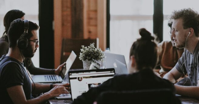 a diverse group of people in business wear working on laptops around an office table