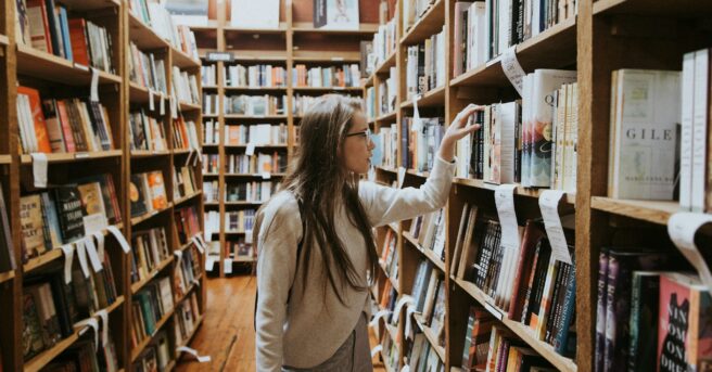 College student with eyeglasses searches for book in campus library