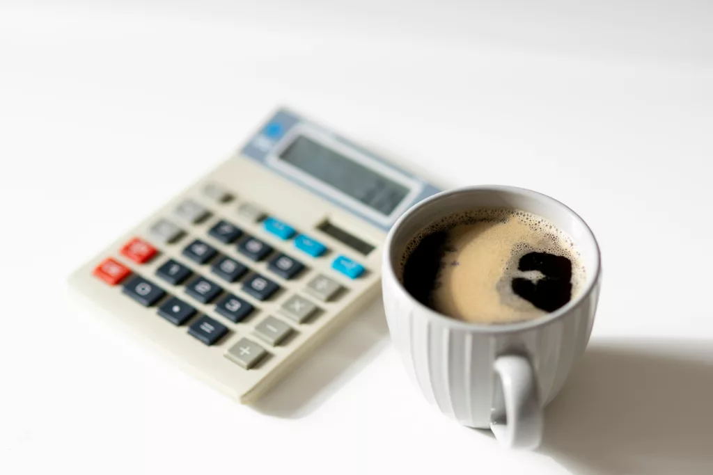 cup of coffee on table beside a calculator