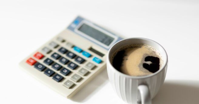 cup of coffee on table beside a calculator