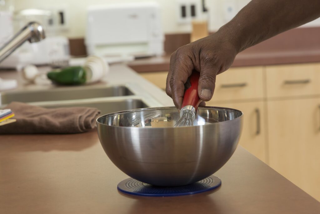 Person whisking in a bowl placed on a non-slip mat