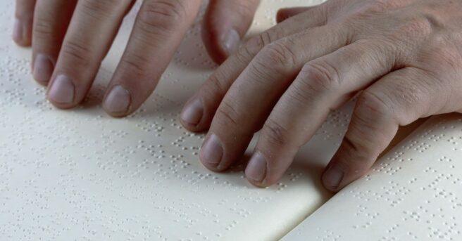 Fingers reading a braille page.
