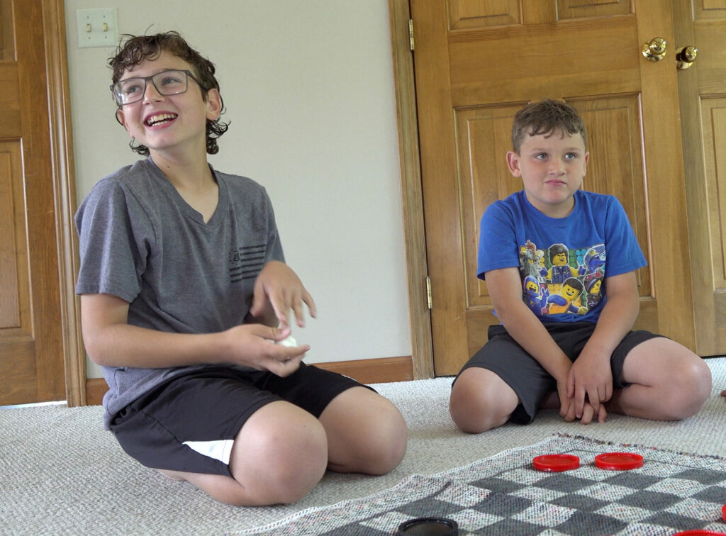 Two boys playing a game of large floor checkers.