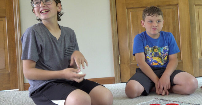 Two boys playing a game of large floor checkers.