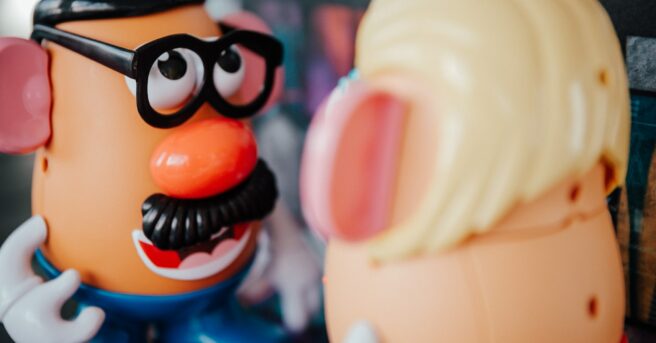 Mr. Potato Head with a hat, glasses and moustache facing a Mrs. Potato head