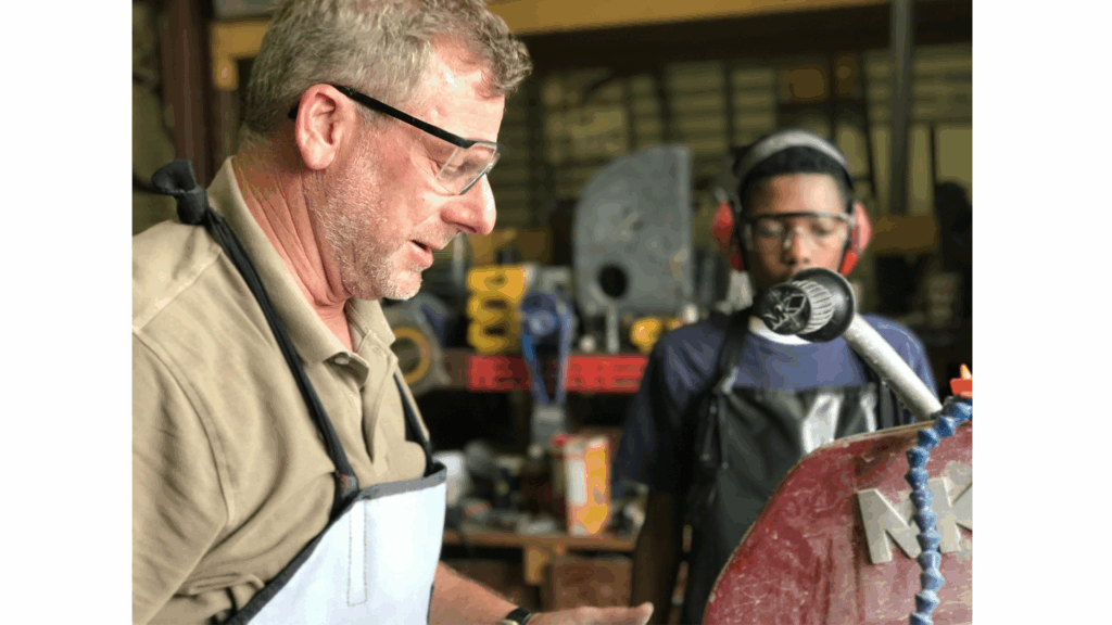 Student and adult work in a shop class with eye protection