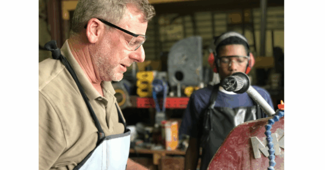 Student and adult work in a shop class with eye protection