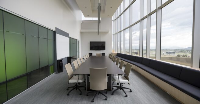 Conference room with a long, narrow table surrounded by rolling chairs