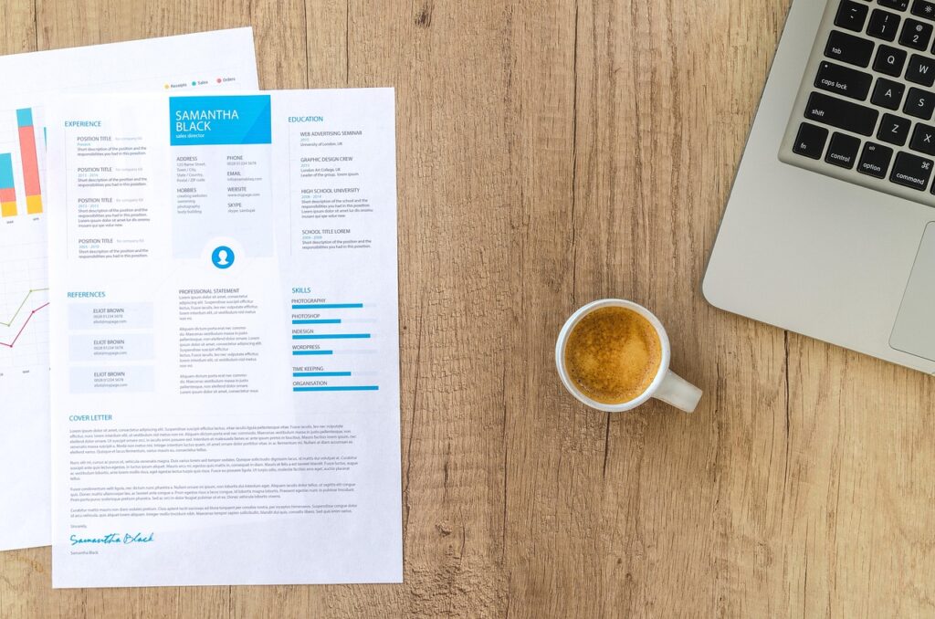 resume on a desk with a laptop and cup of coffee