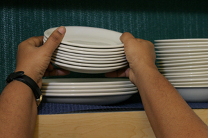 Person putting stack of dishes away 