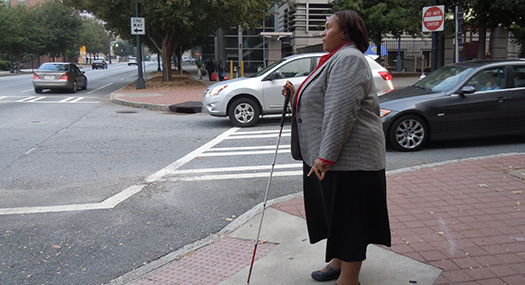 woman with white cane extended getting ready to cross the street