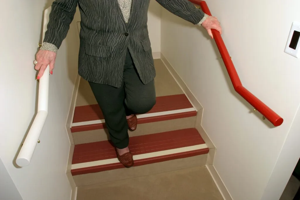Person walking down dark wooden stairs with high-contrast white stripes