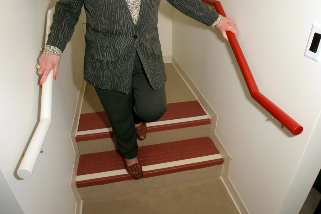 Person walking down dark wooden stairs with high-contrast white stripes