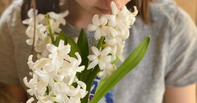 A young girl smelling a bouquet of white flowers