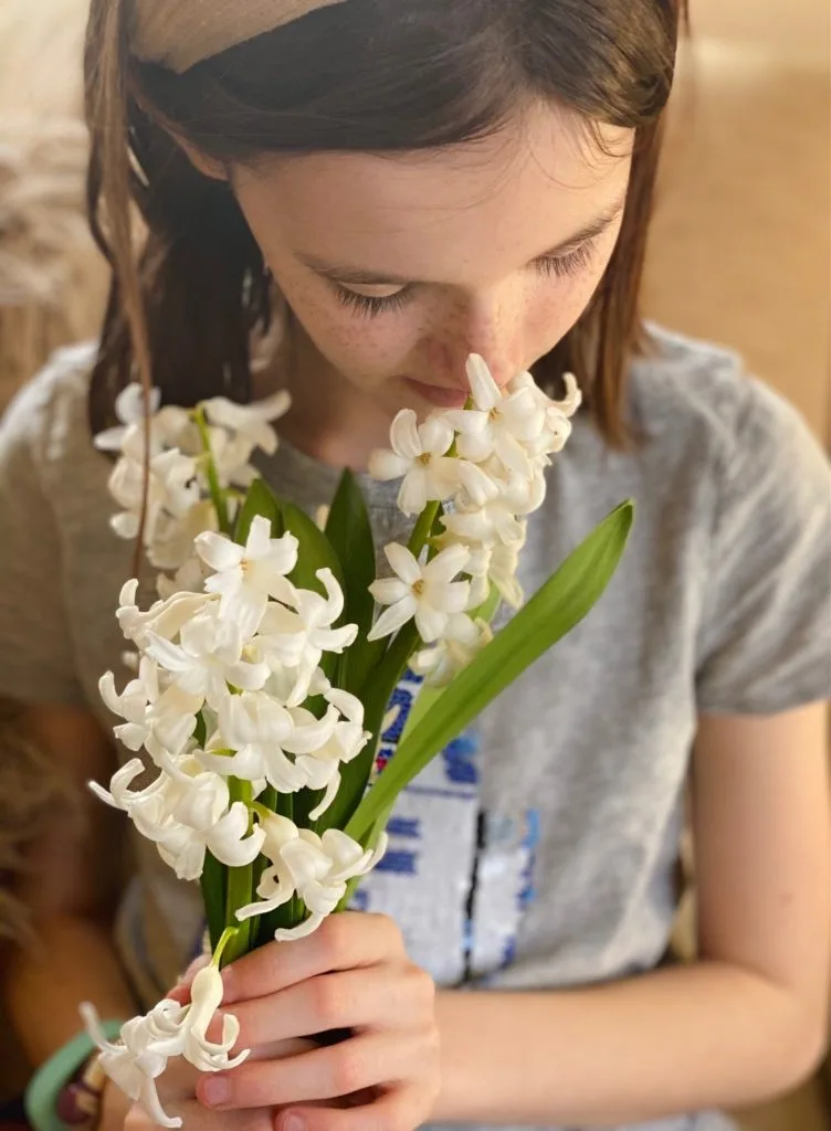 A young girl smelling a bouquet of white flowers