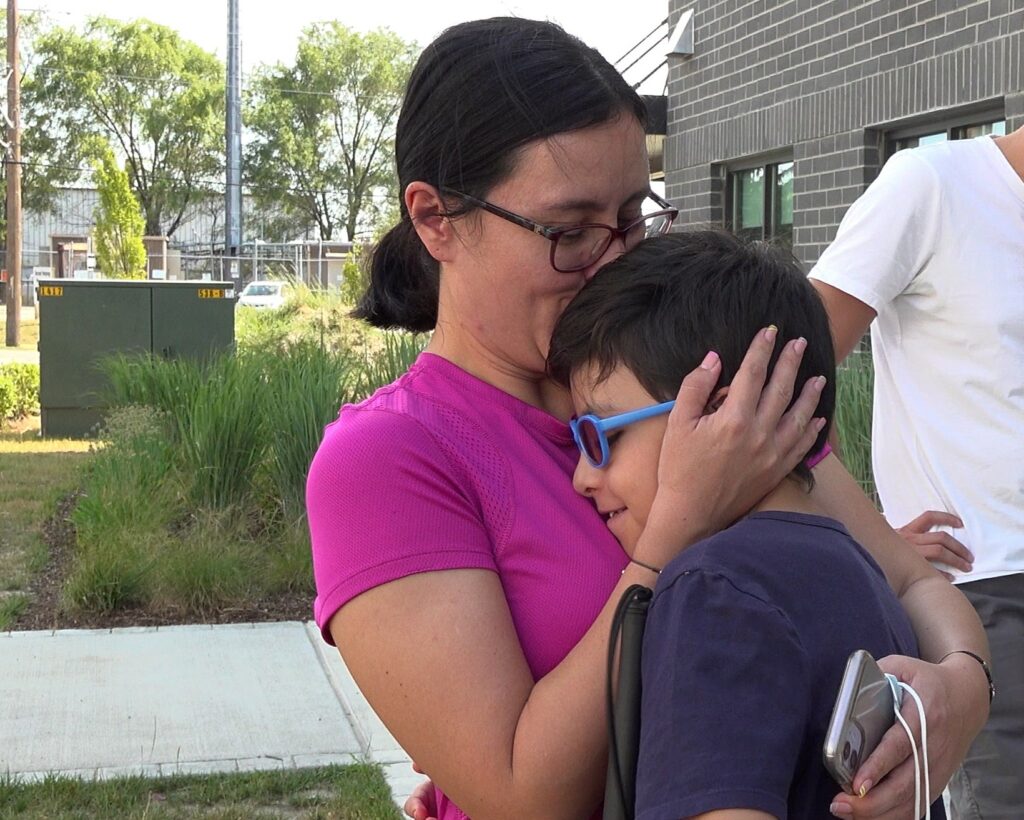 A mom hugging her son outside.