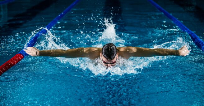 A person swimming the butterfly stroke in a pool lane